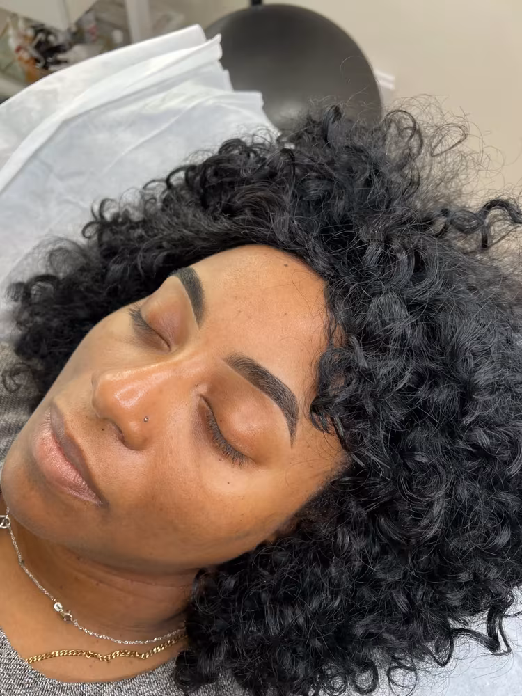 Henna brow tint and shaping result, full, defined dark brows on a client with curly black hair