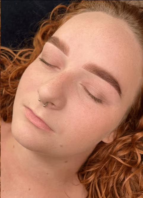 Henna brow tint and shaping result, soft auburn brows on a client with red curly hair