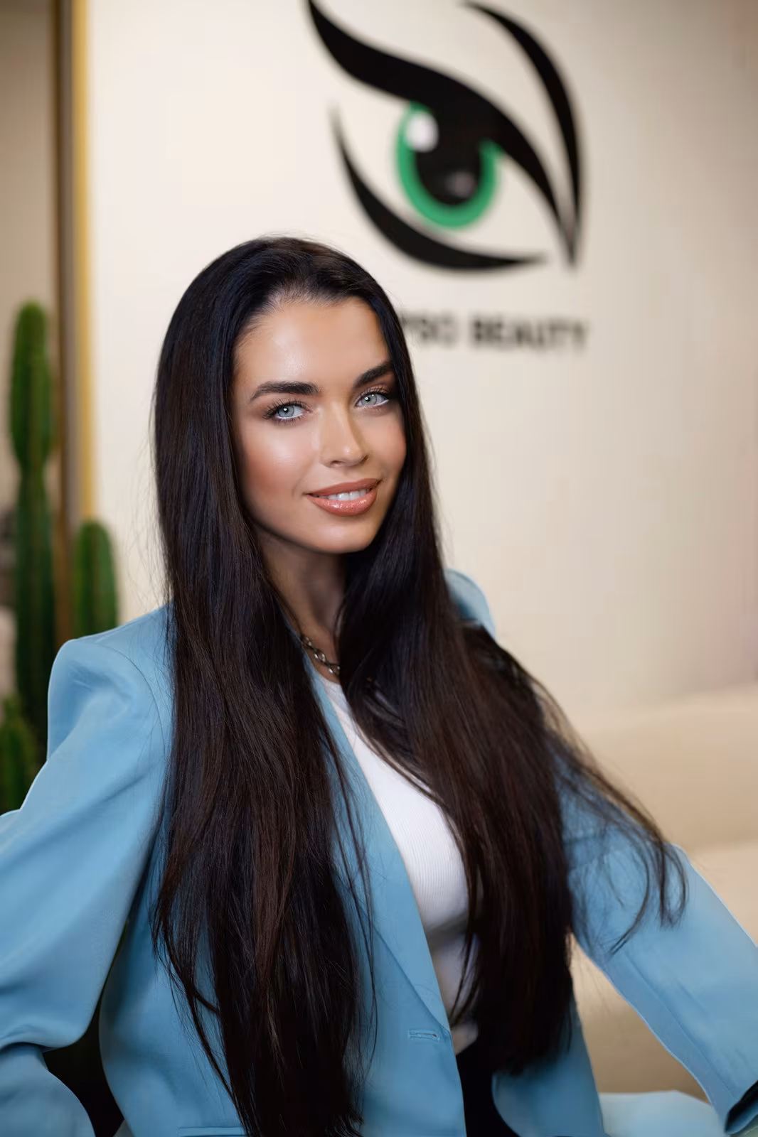 Yulia Alpeza, founder and permanent makeup artist at Calypso Beauty, in front of the studio’s wall logo