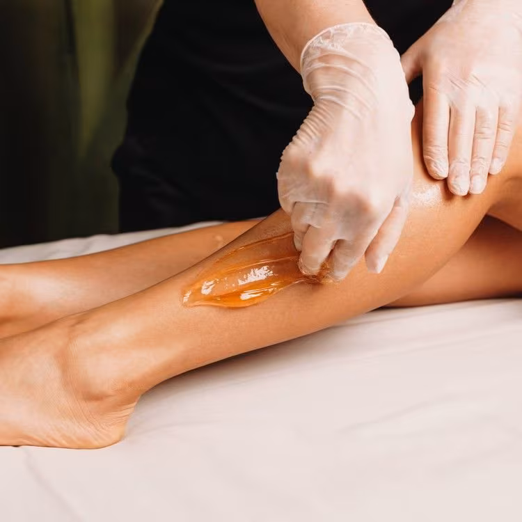 Sugaring paste being applied to a client’s legs at Calypso Beauty