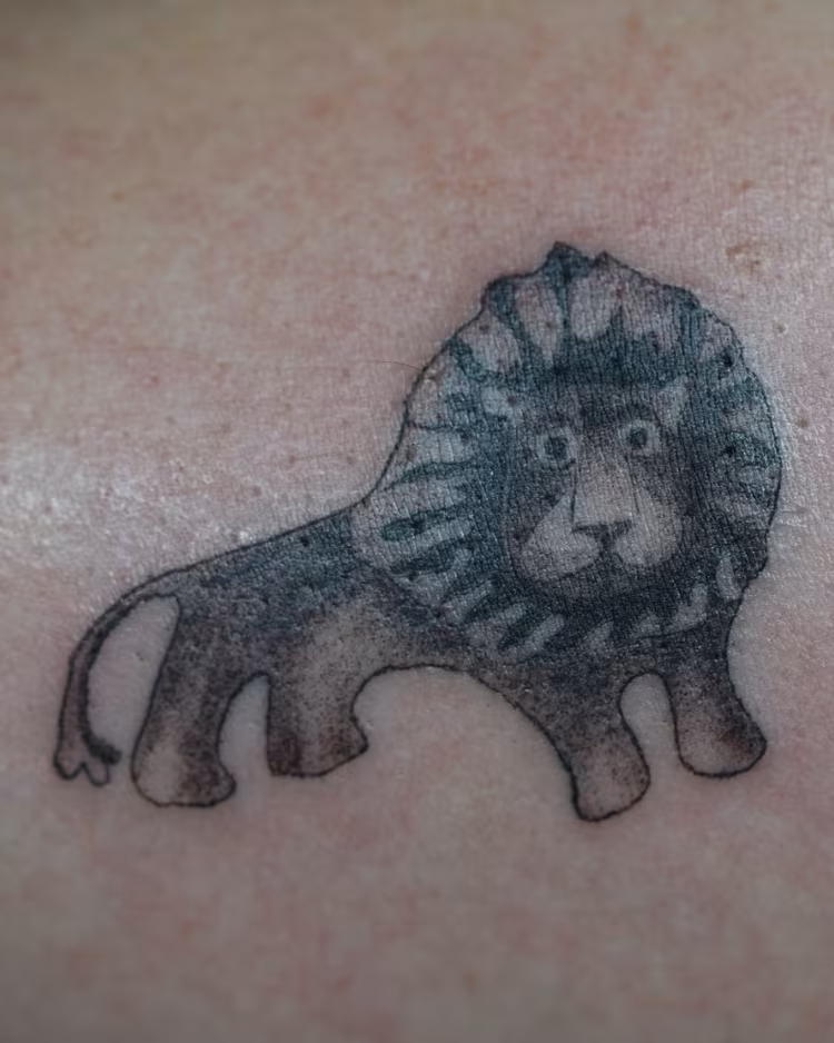 Small shaded lion tattoo designed after a client’s lion charm necklace